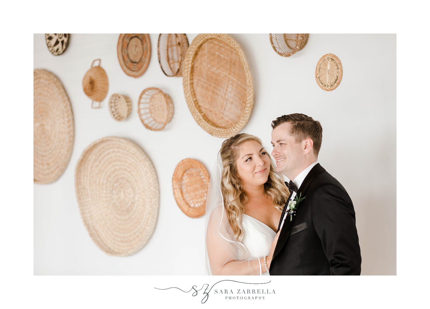 bride looks at husband during portraits along wall inside Newport Beach House