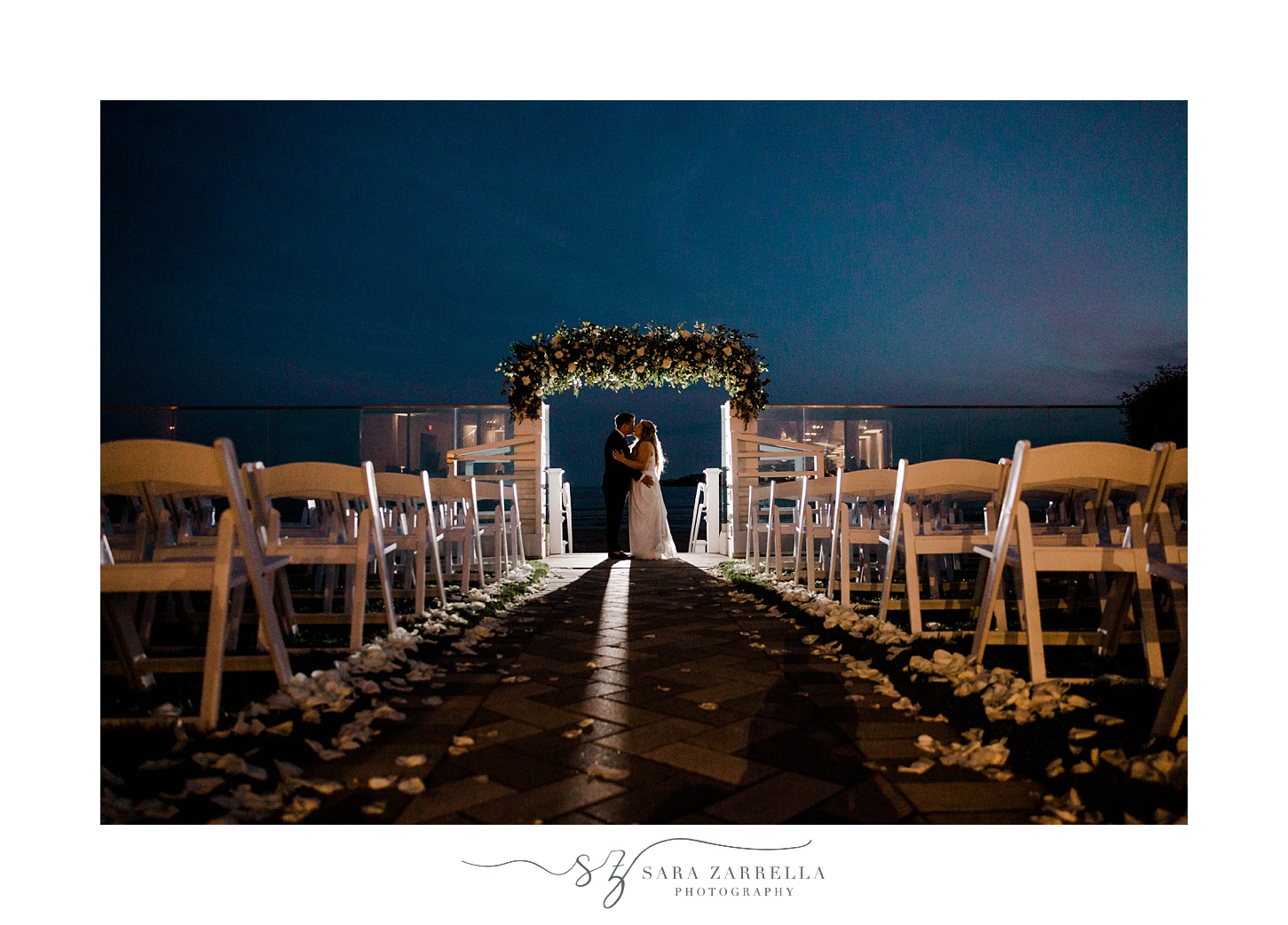 bride and groom pose under arbor at Newport Beach House at night
