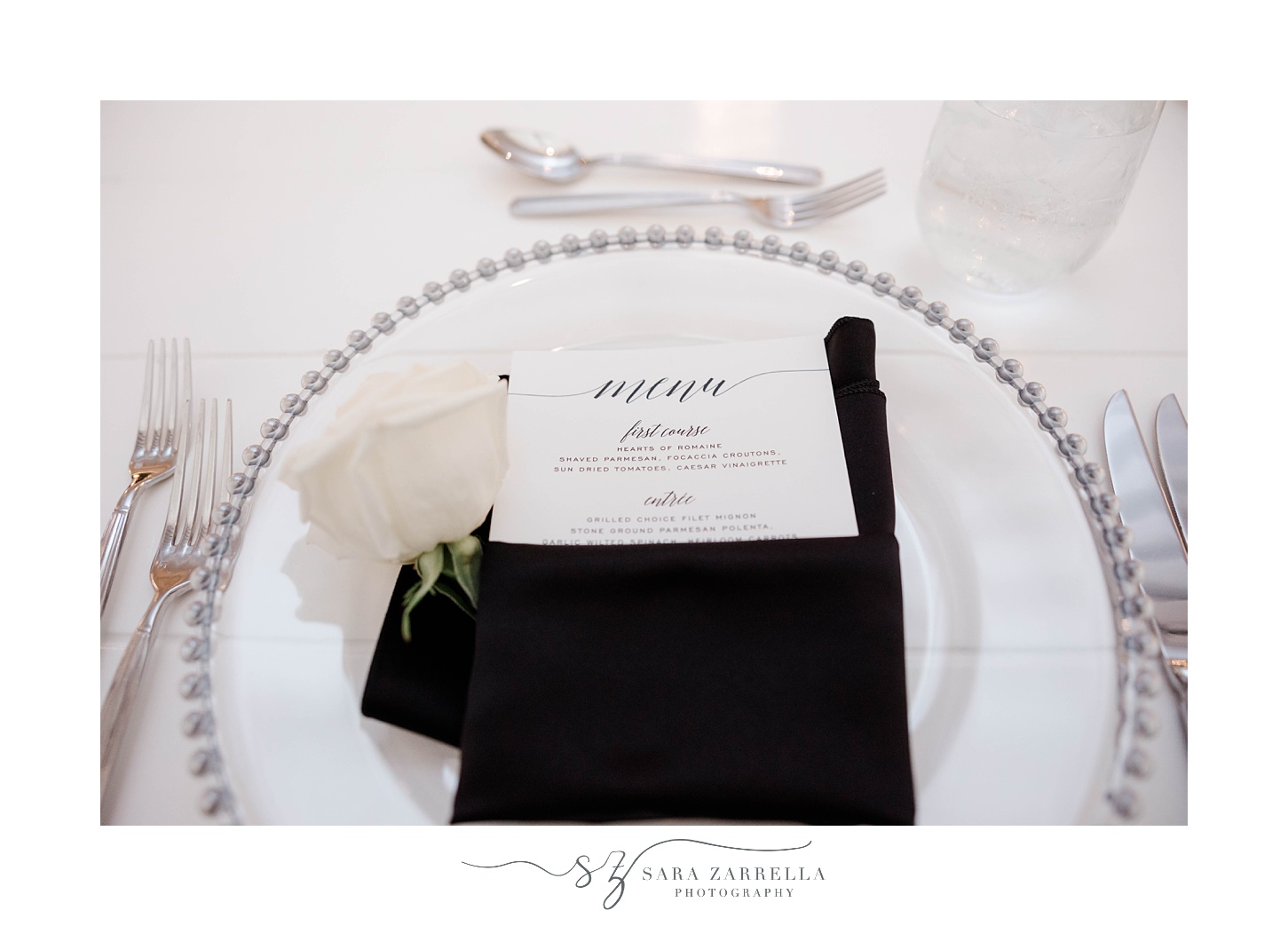 place setting on plate with silver rim and black napkin