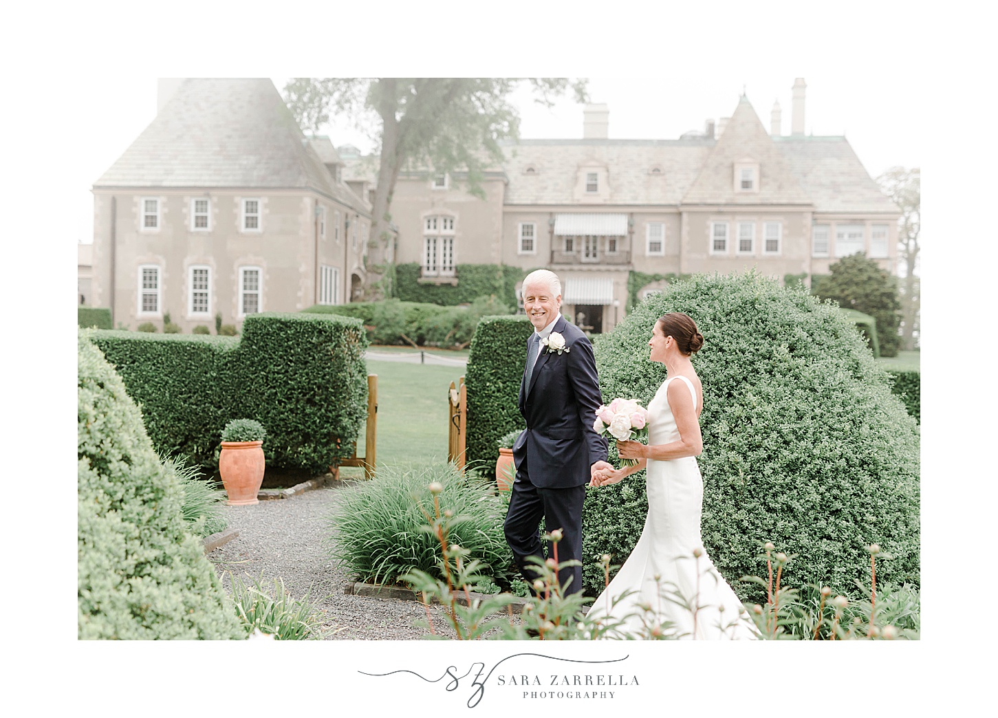 newlyweds walk through gardens in front of The Chanler