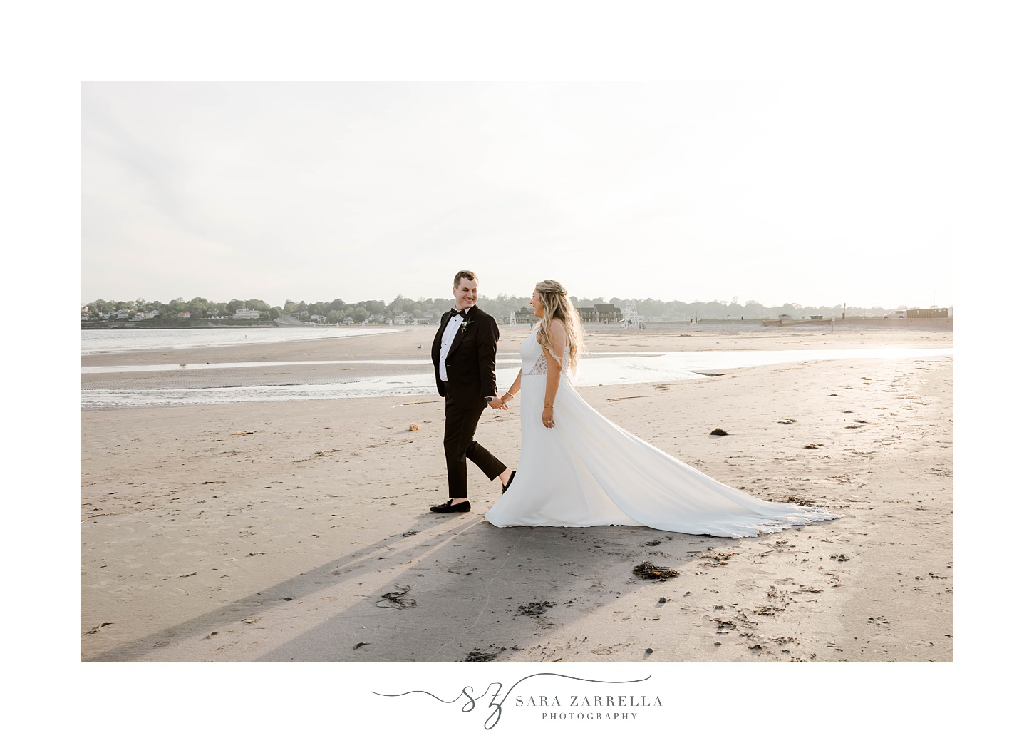 bride and groom hold hands walking on Newport RI beach