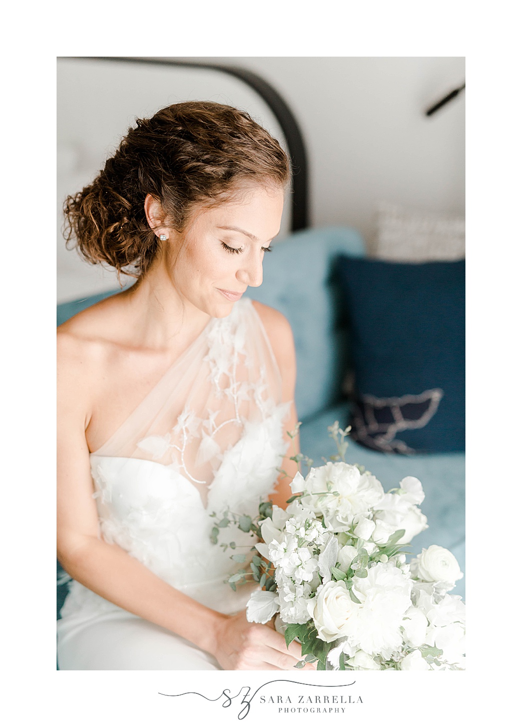 bride sits looking at white bouquet