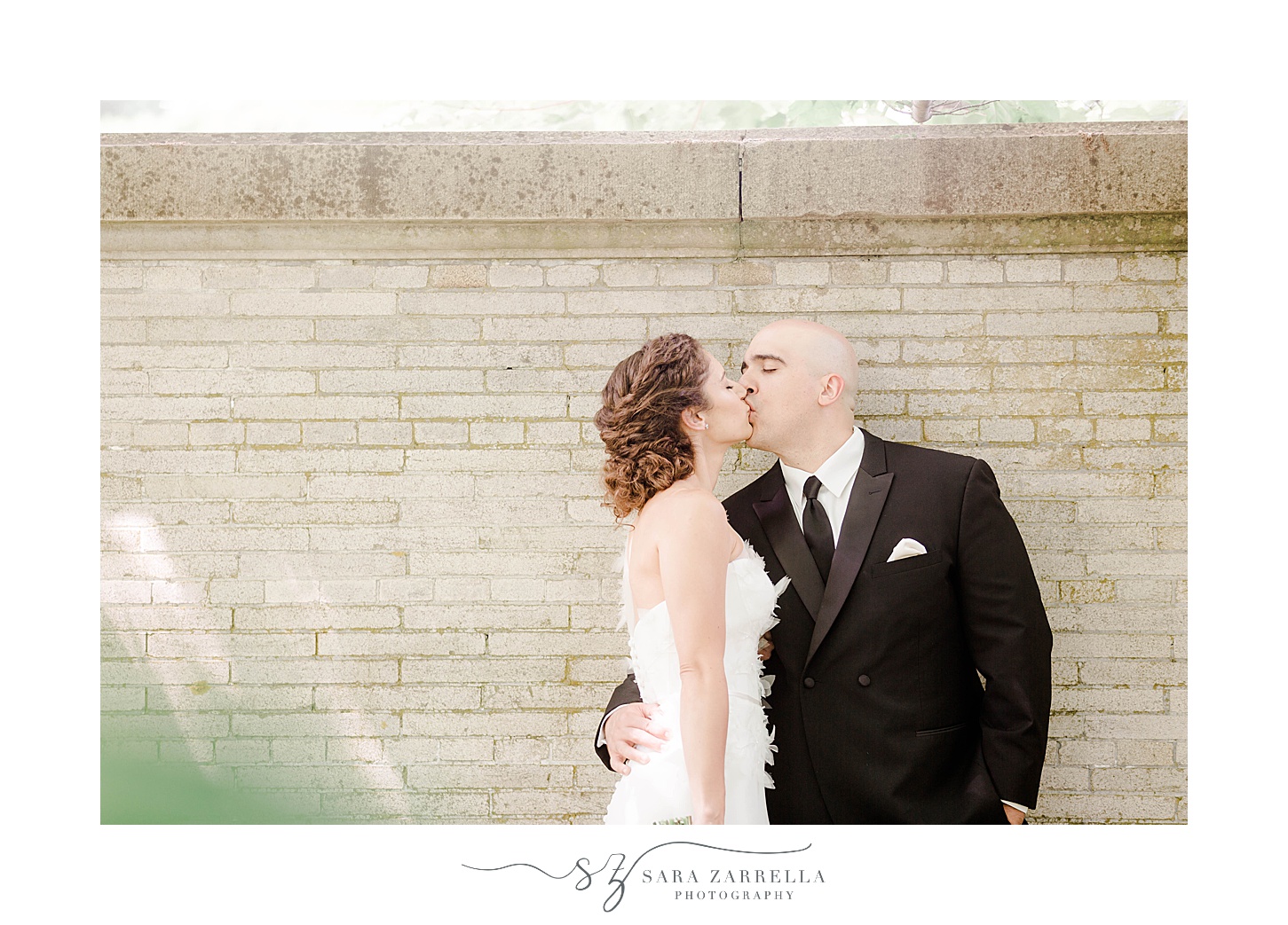 bride and groom pose by brick wall at The Elms