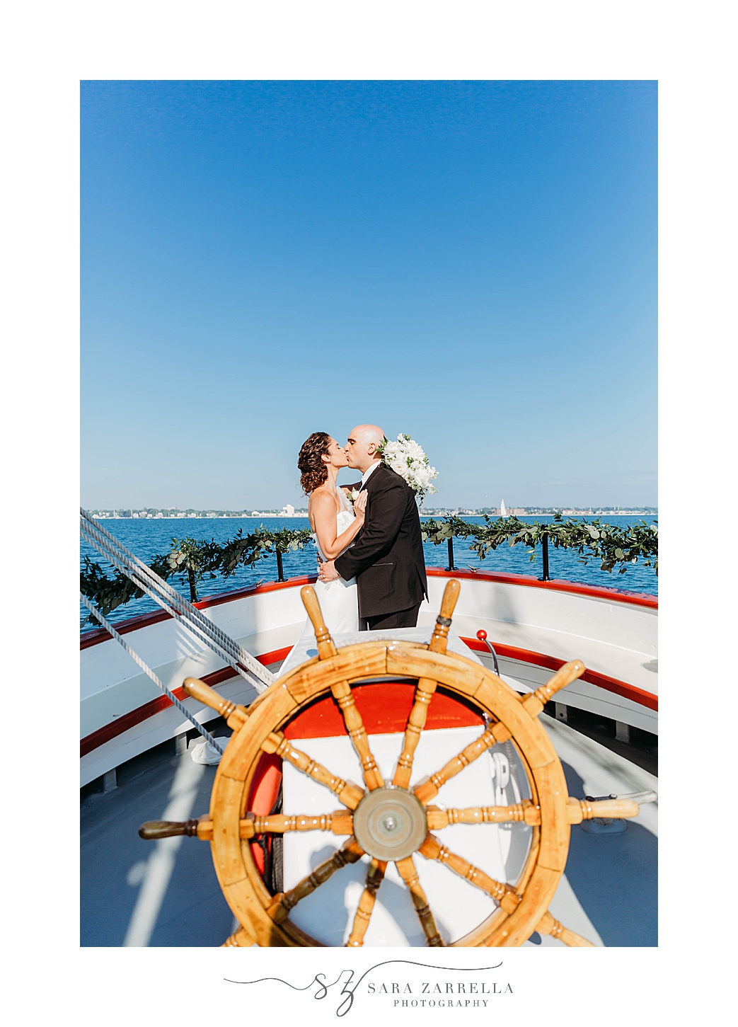 bride and groom kiss by steering wheel of Schooner Aurora