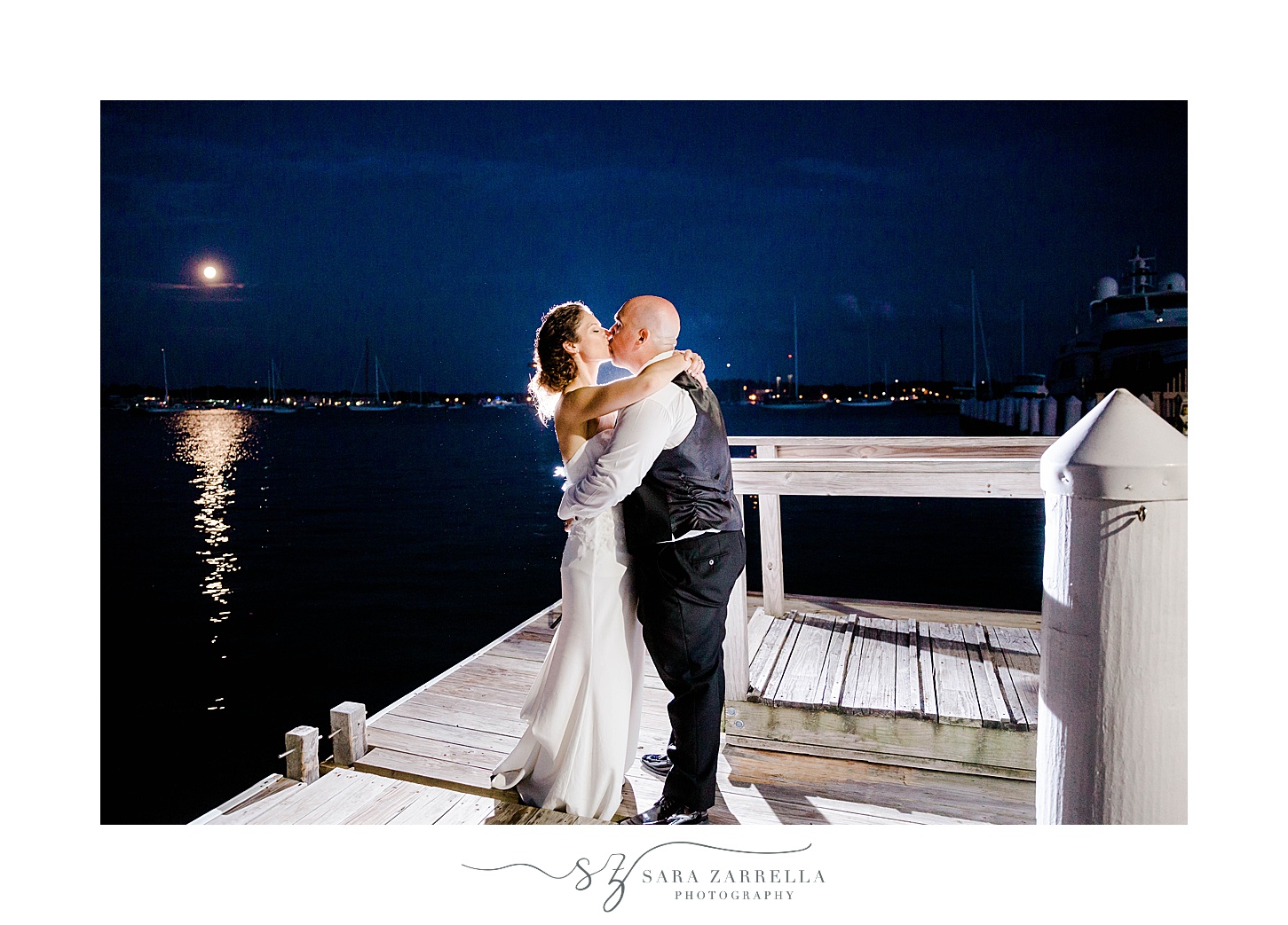 couple hugs on dock during nighttime wedding portraits in Newport RI