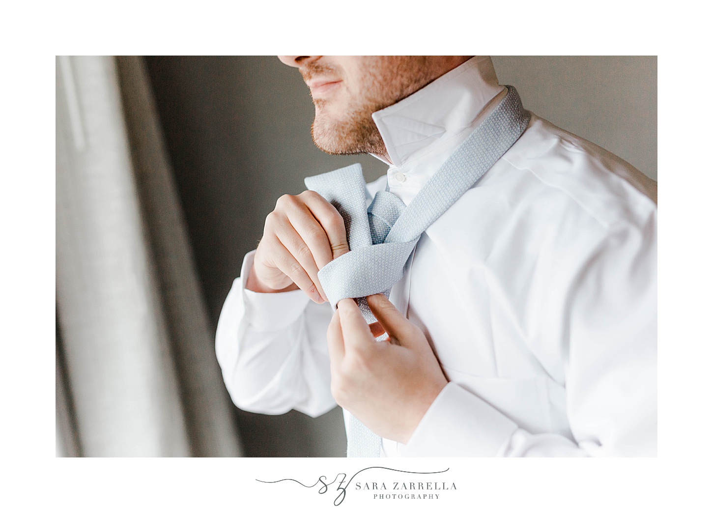 groom ties tie before RI wedding day at Squantum Association