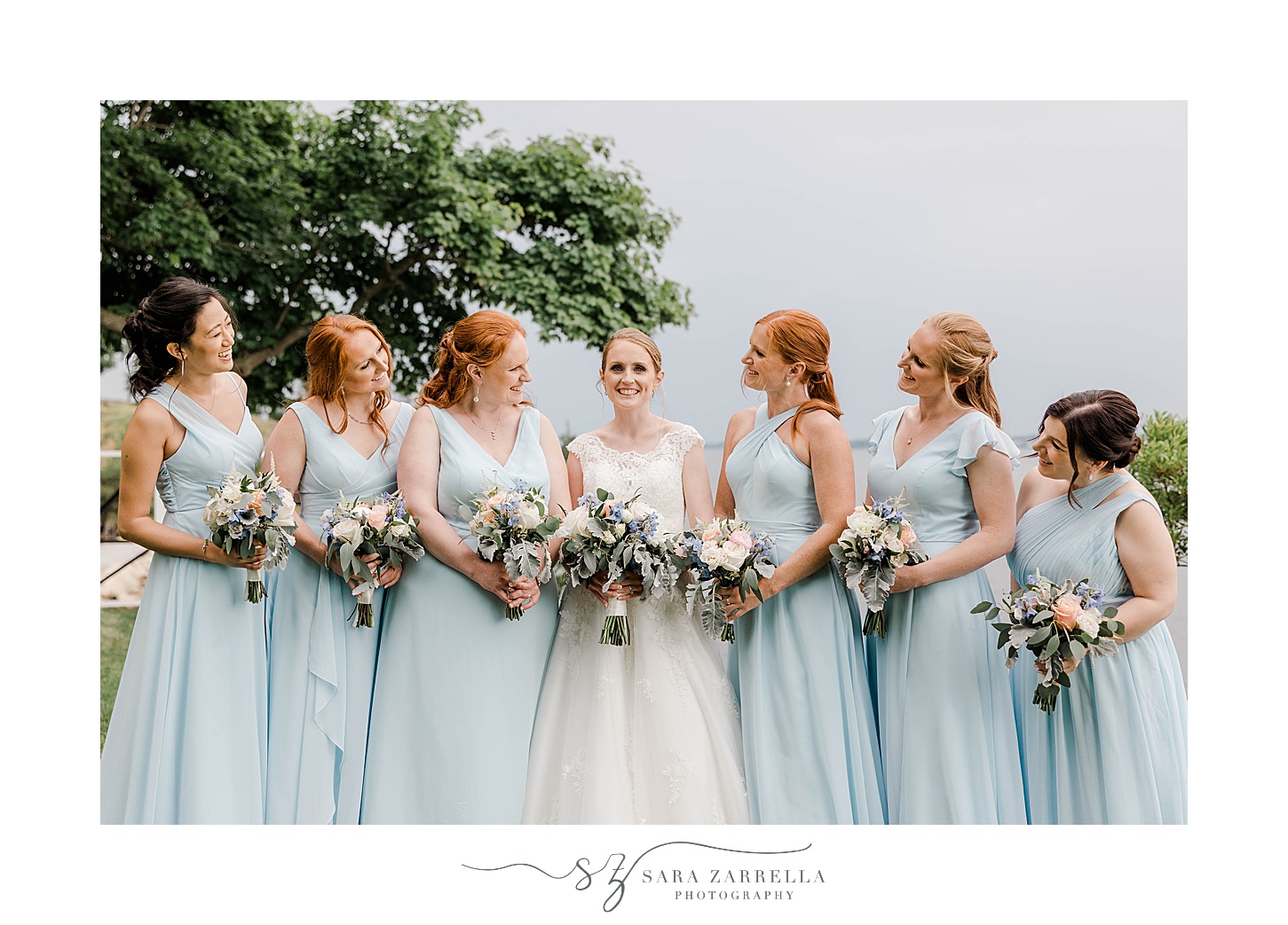 bride smiles in middle of bridesmaids in light blue gowns