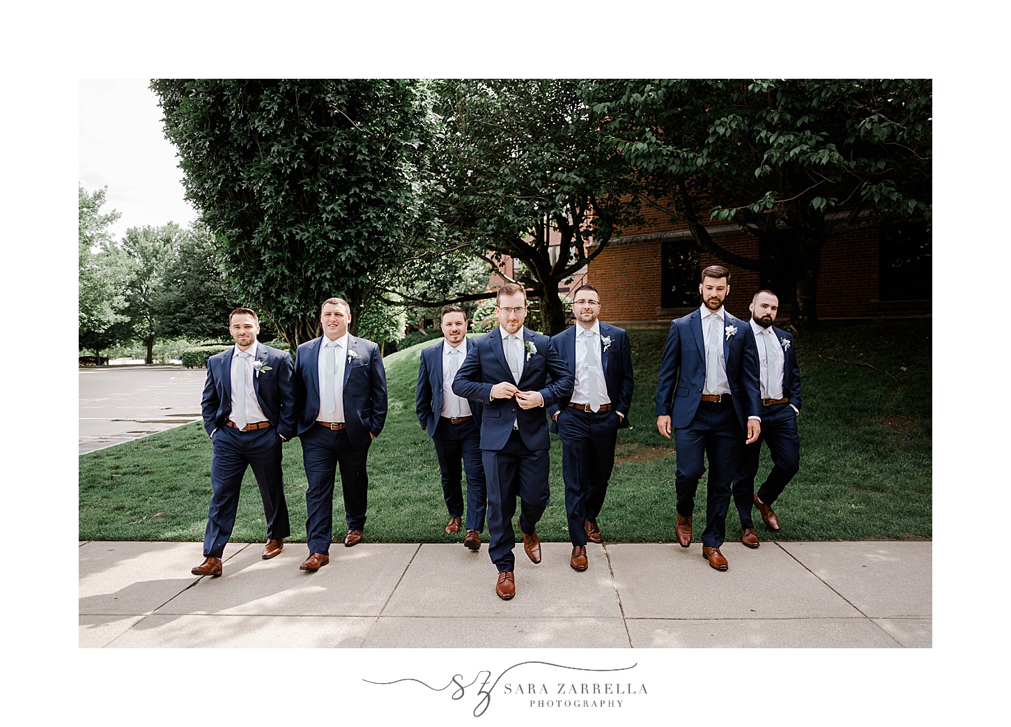 groom walks with groomsmen in navy suits outside Squantum Association