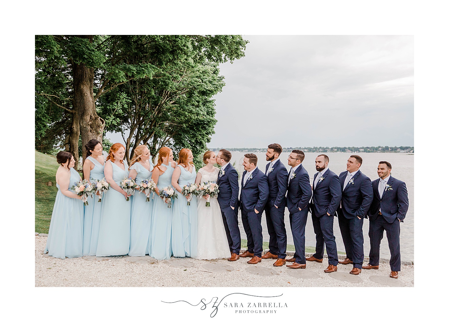 bride and groom stand with wedding party by water at Squantum Association