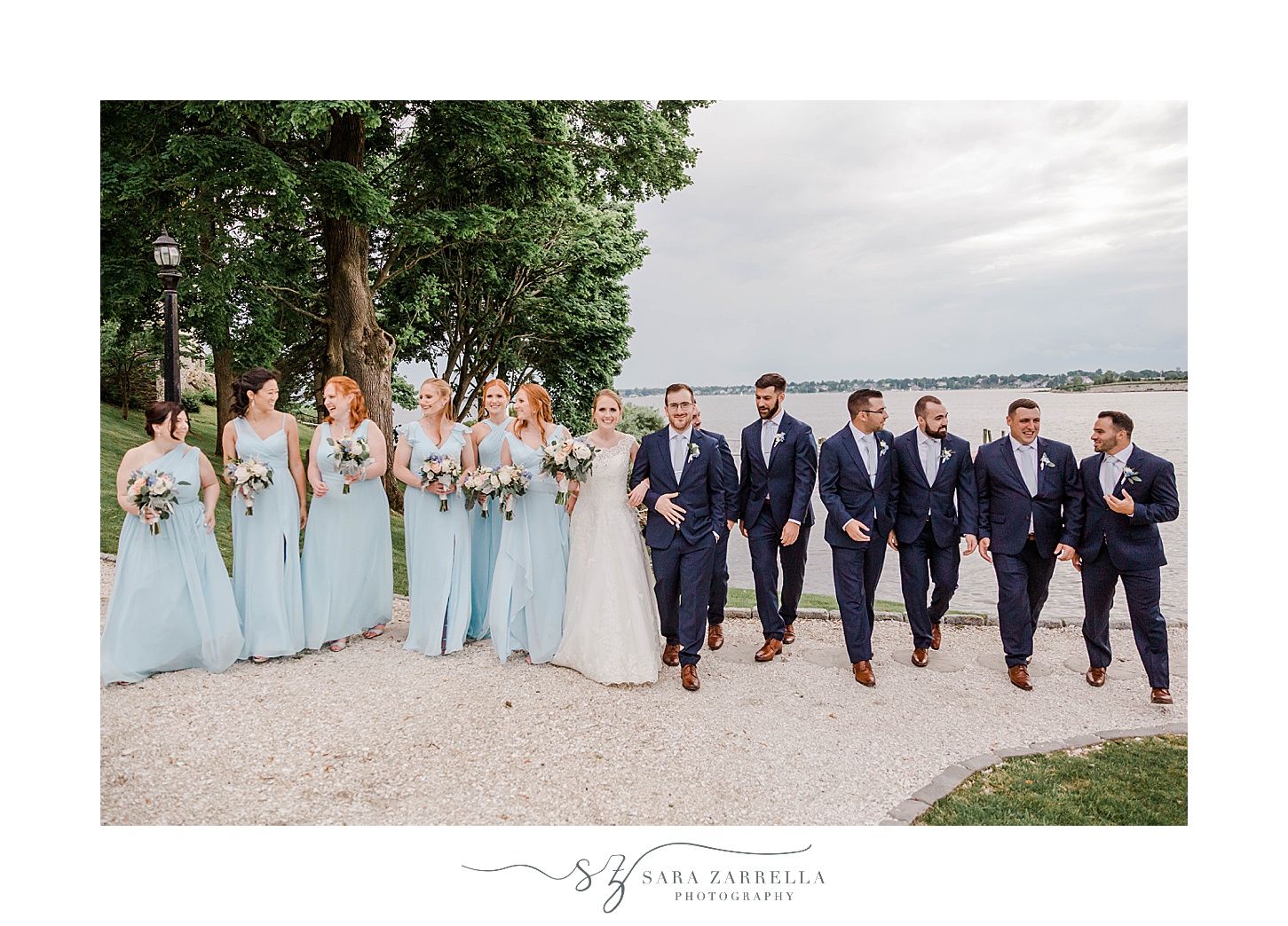 bride and groom walk in front of water with wedding party at Squantum Association