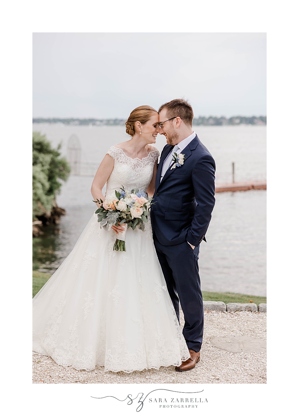 newlyweds lead heads together along waterfront at Squantum Association