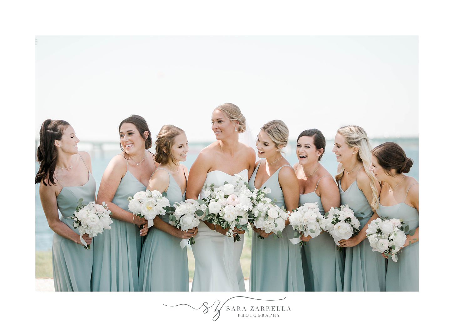 bride and bridesmaids laugh together holding white bouquets