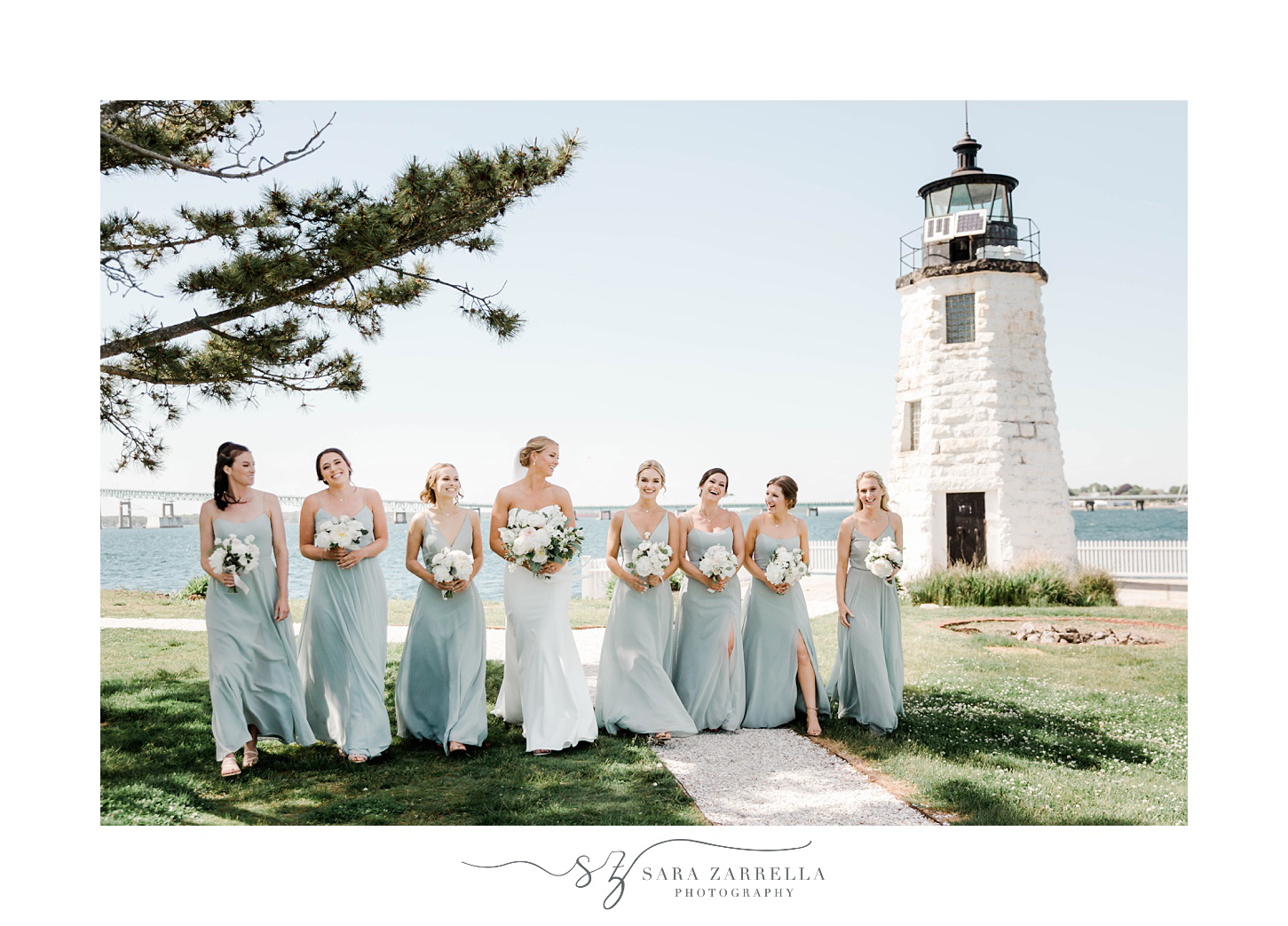 bride and bridesmaids in pale green gowns walk near Newport Lighthouse 