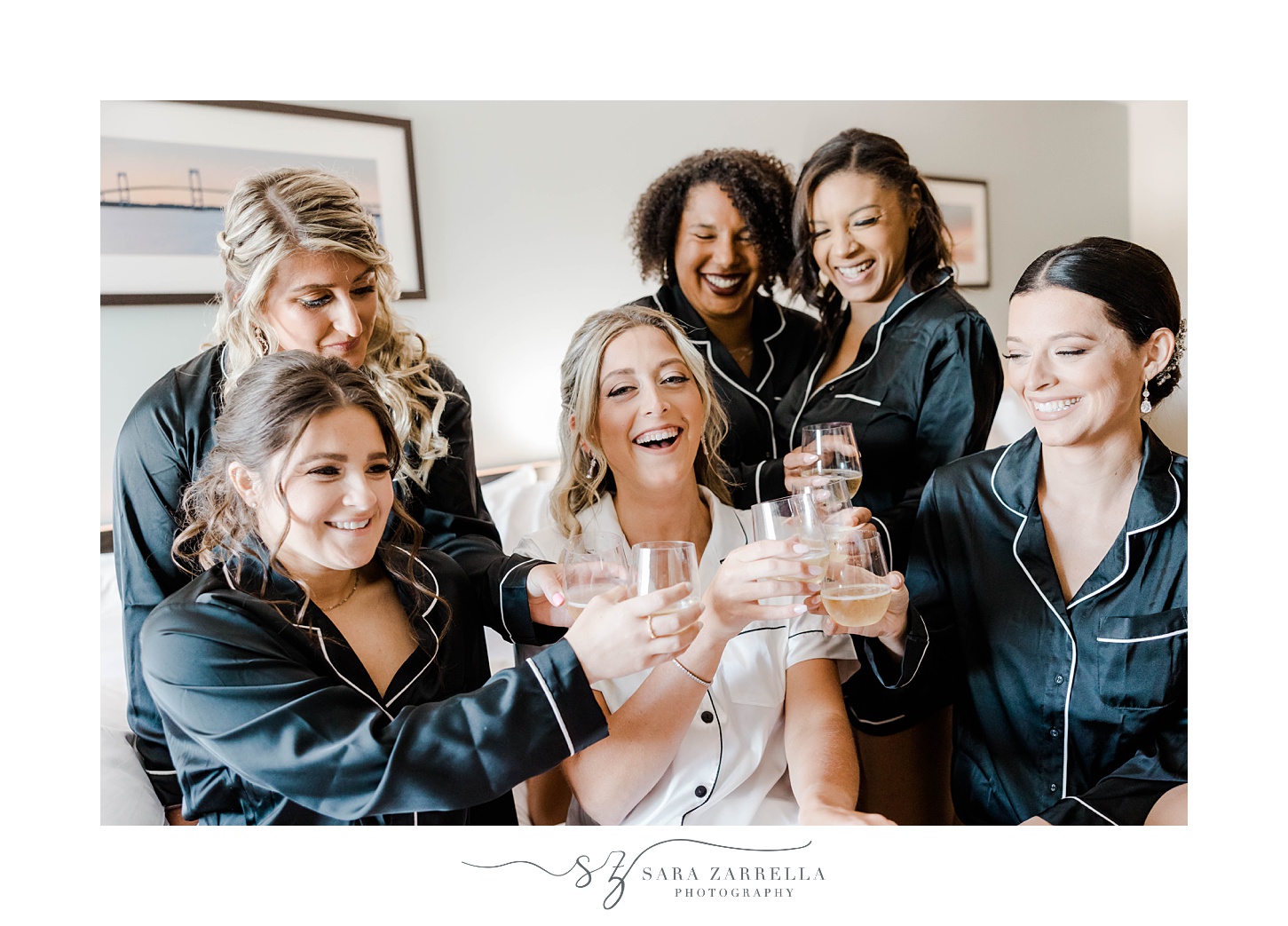 bride and bridesmaids laugh toasting champagne