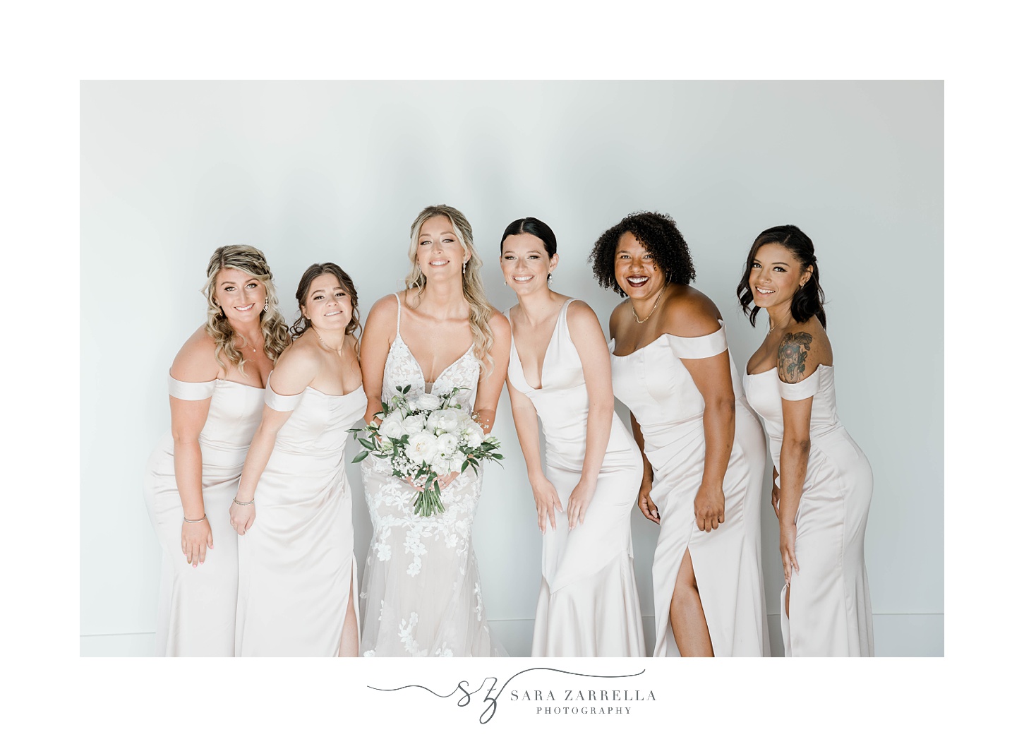 bride and bridesmaids pose agains white wall at Newport Beach House
