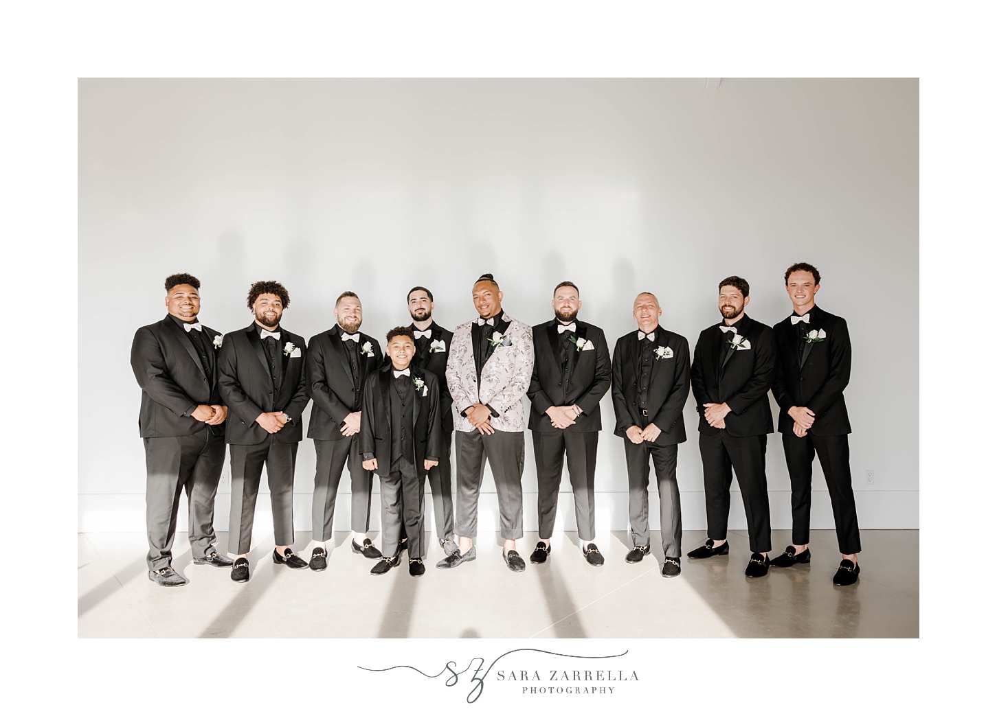 groom stands with groomsmen in black suits at Newport Beach House