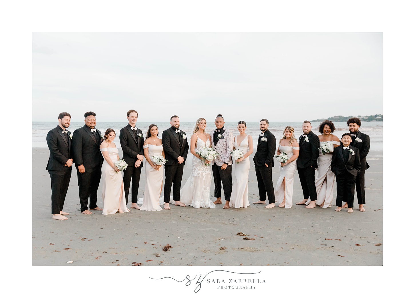 bride and groom stand on Newport Beach with wedding party in black and pink 
