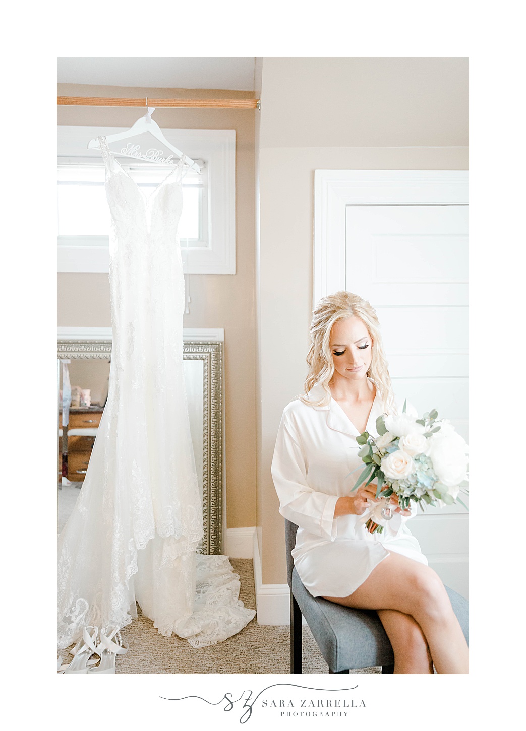bride sits by wedding dress holding bouquet 