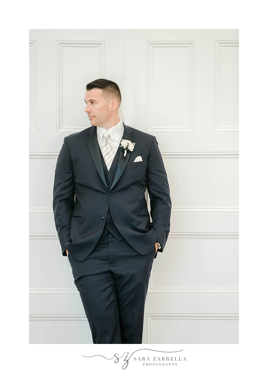groom leans against white wall at Squantum Association