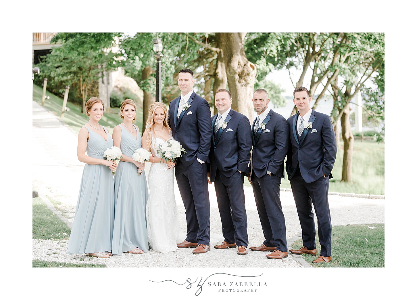 newlyweds stand with bridal party in blue gowns and suits