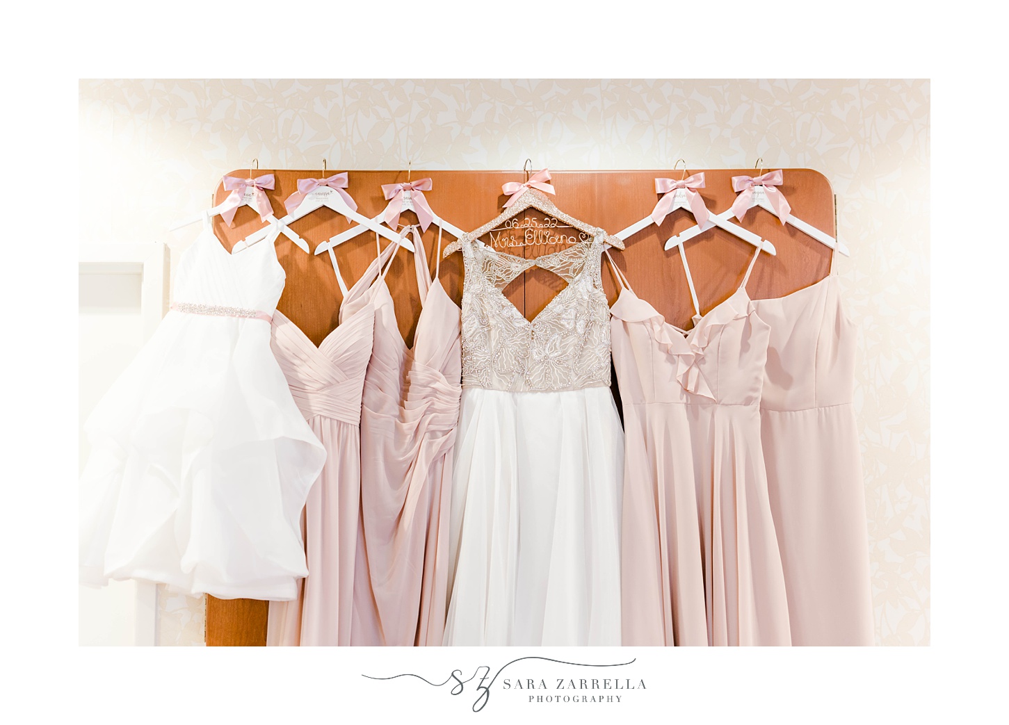 bride's dress hangs with bridesmaids' pink gowns