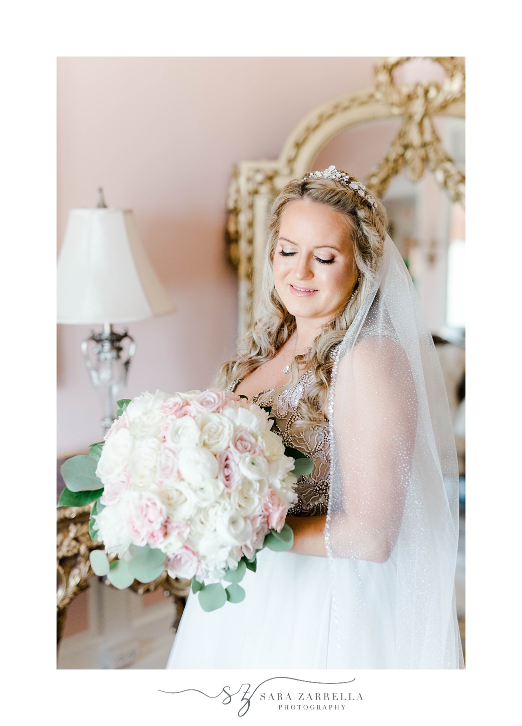 bride looks over shoulder at pink and white bouquet in bridal suite at Aldrich Mansion