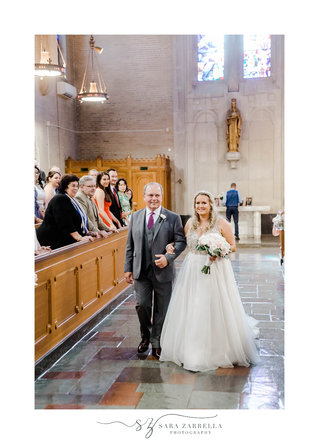 bride walks up aisle with father during traditional wedding ceremony in Rhode Island church