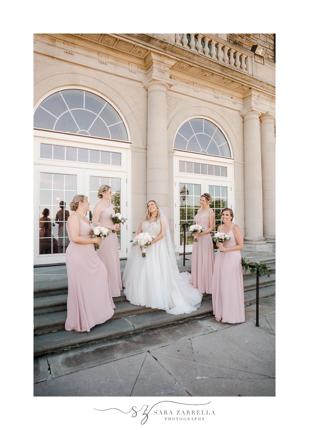 bride poses with bridesmaids on steps of Aldrich Mansion