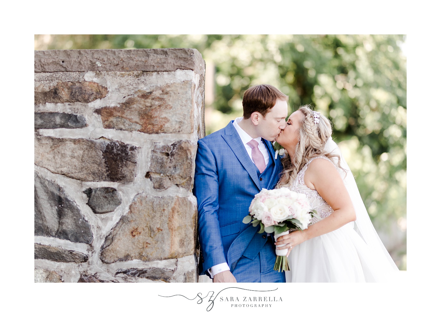newlyweds kiss by stone wall in Warwick RI garden