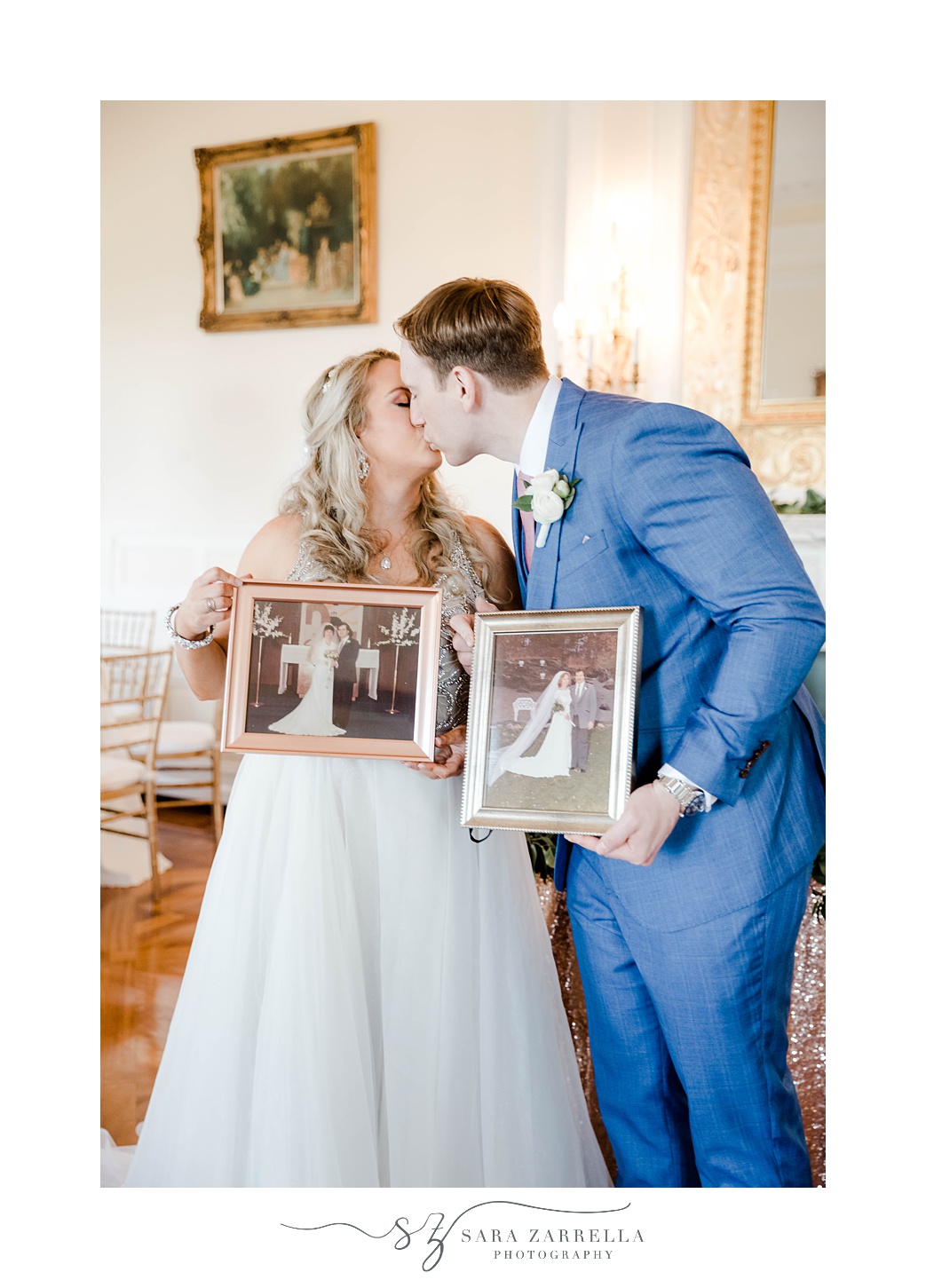 couple kisses while holding their parents' wedding photos