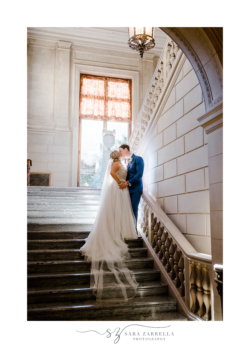 bride and groom stand on steps kissing inside Aldrich Mansion