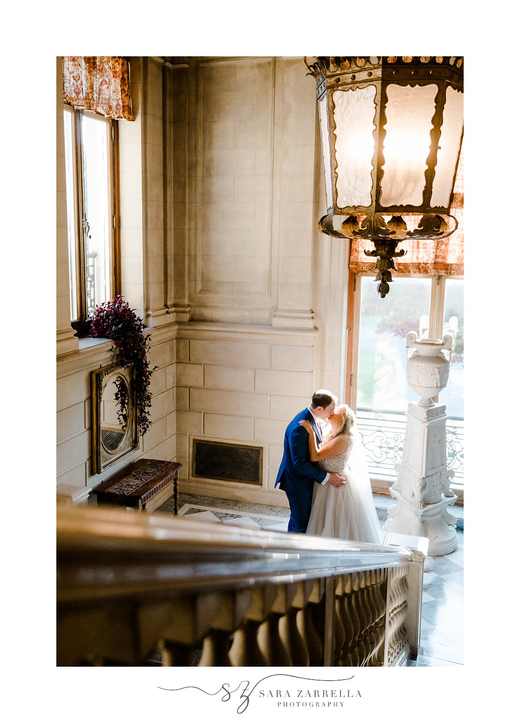 newlyweds kiss at base of staircase in Warwick RI mansion