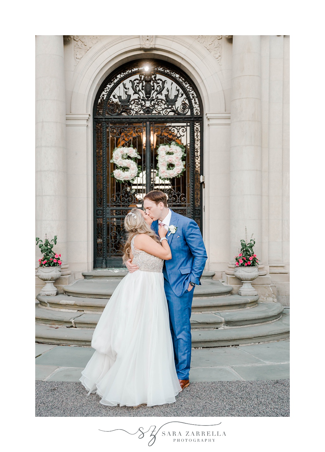 bride and groom kiss outside doors with "S" and "B" floral arrangement hanging
