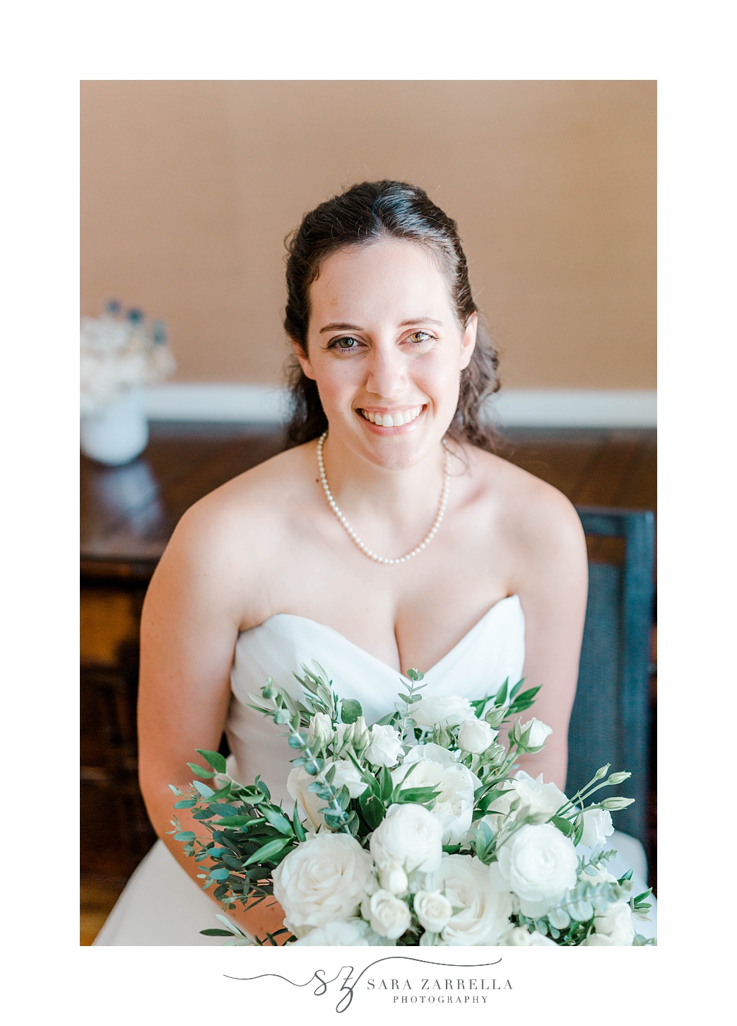 bride sits in strapless wedding gown smiling 