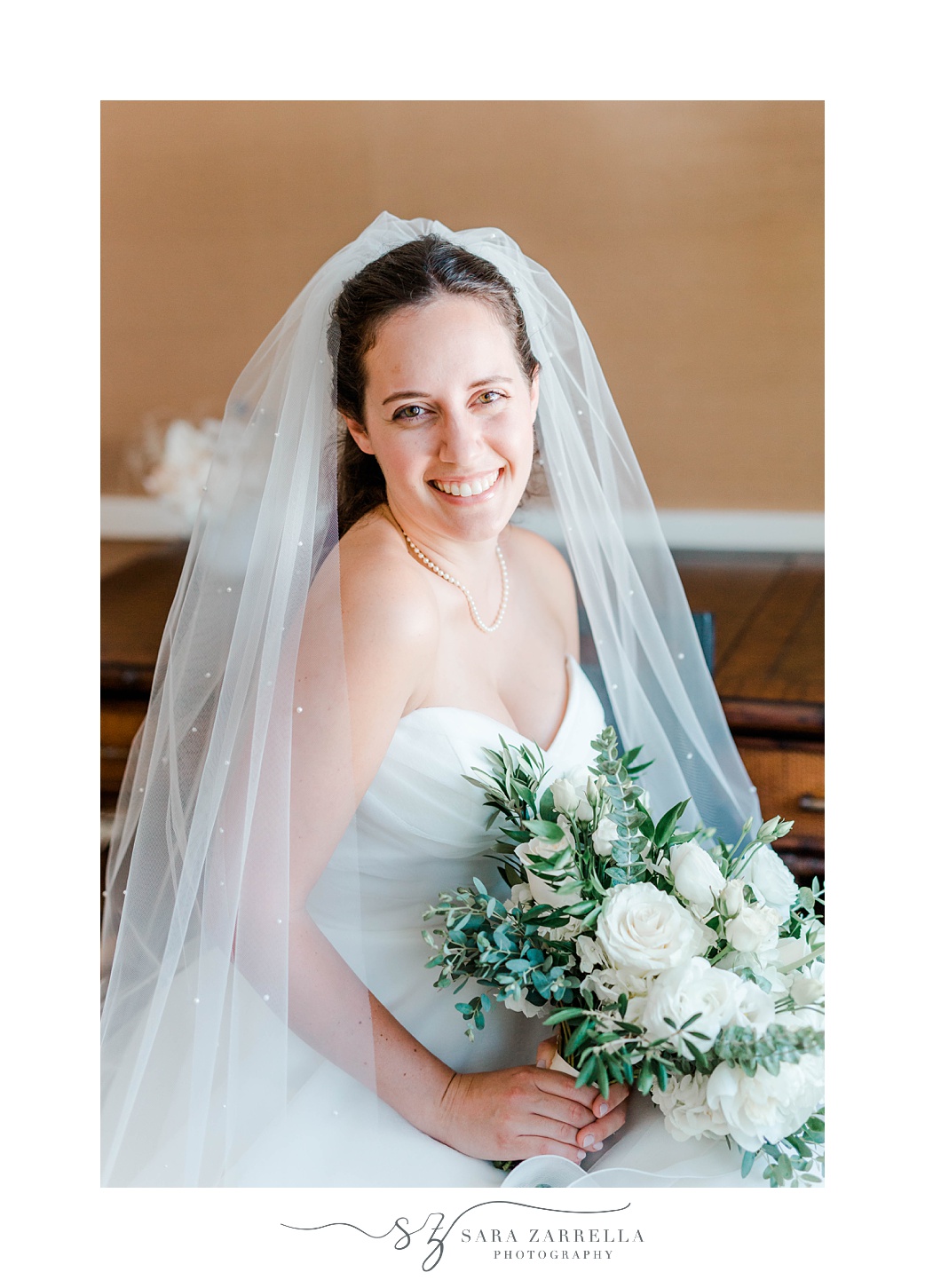 bride smiles with veil around shoulders in strapless wedding gown