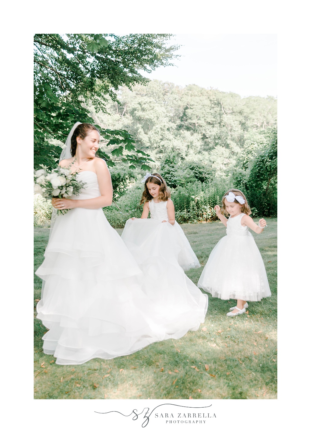 flower girls help bride with wedding gown