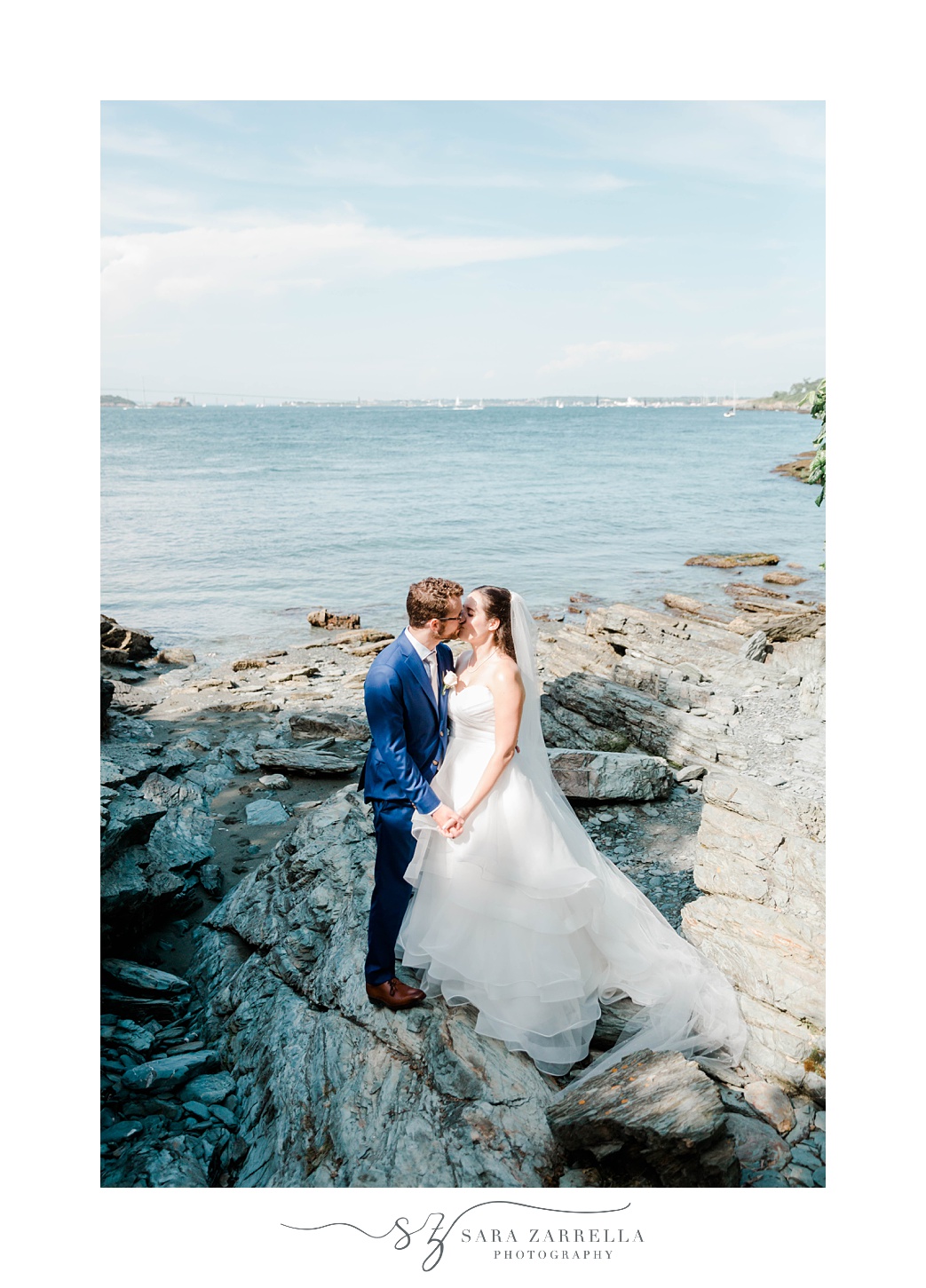 bride and groom kiss on stones in Rhode Island