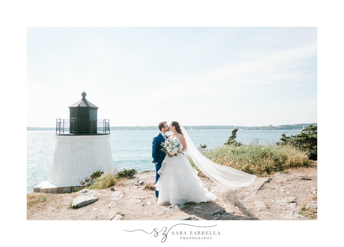 bride and groom kiss with bride's veil floating behind them at lighthouse by Castle Hill Inn