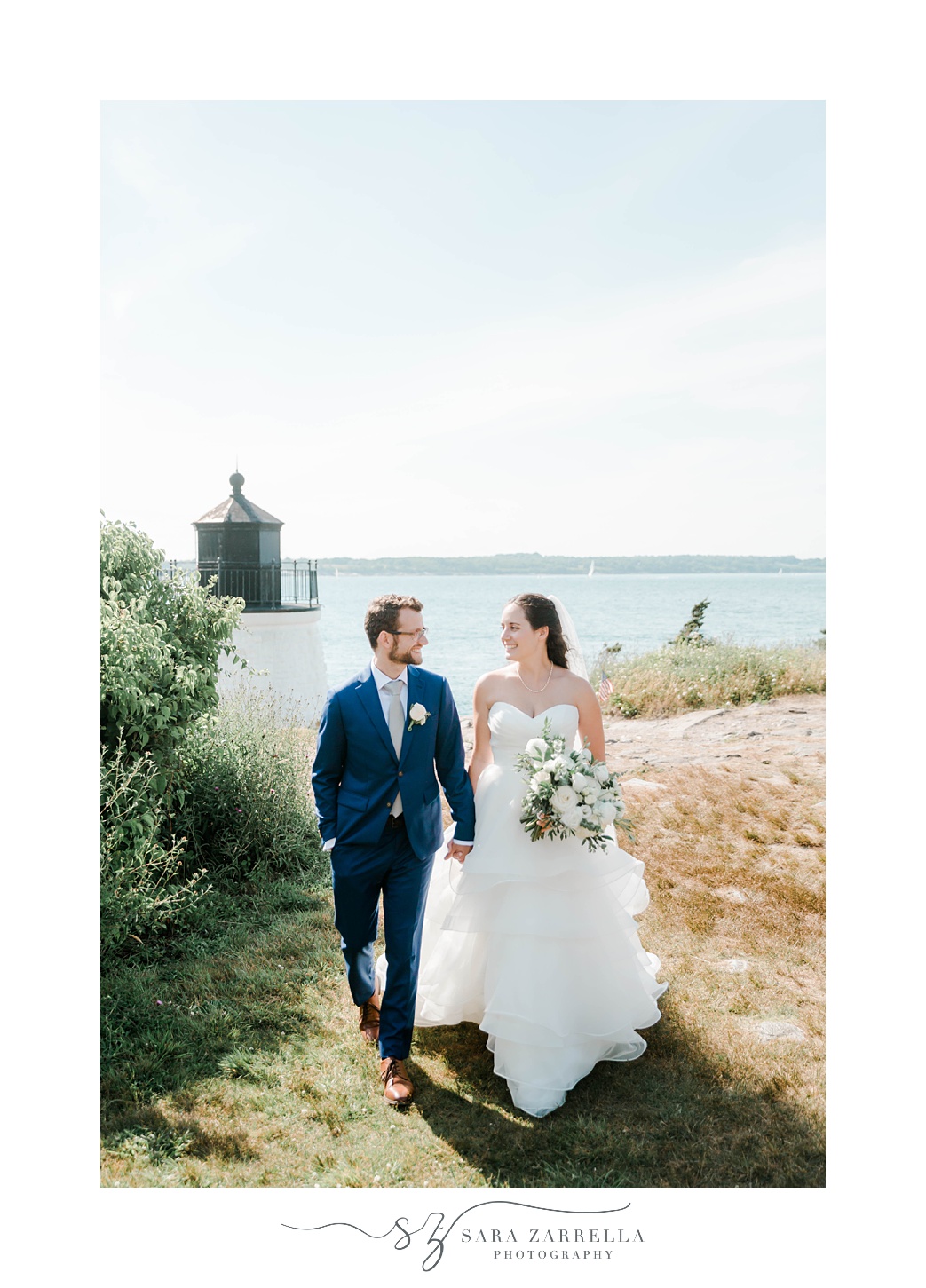 bride and groom hold hands by lighthouse in Castle Hill Inn