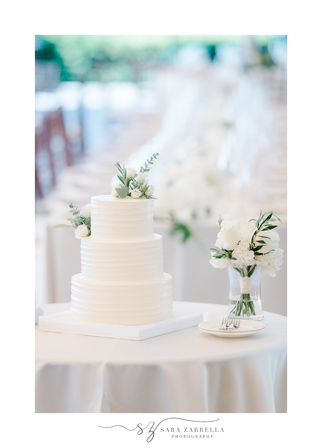 wedding cake sits on table with ivory flowers 