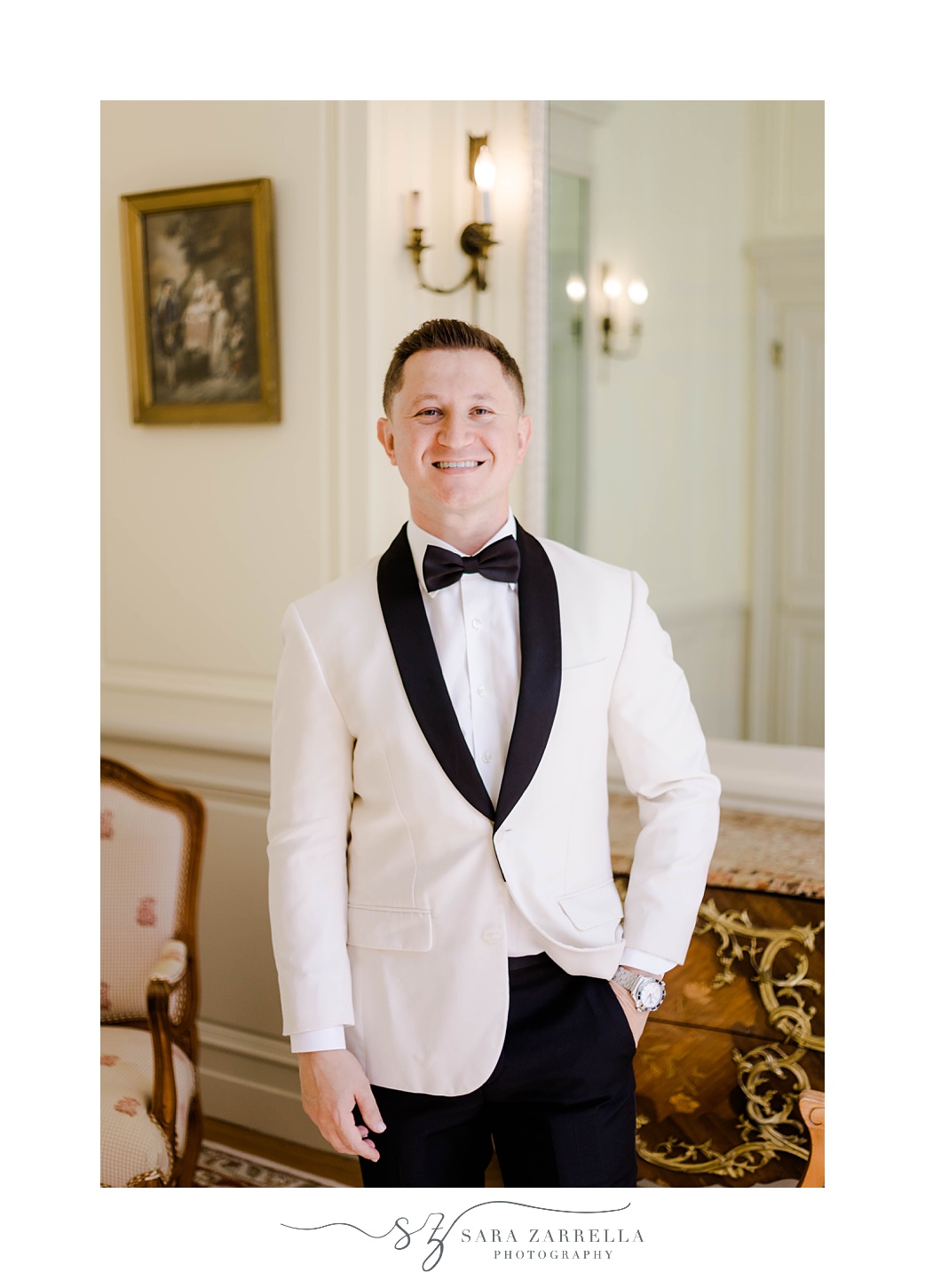groom stands in white tux jacket with black lapels
