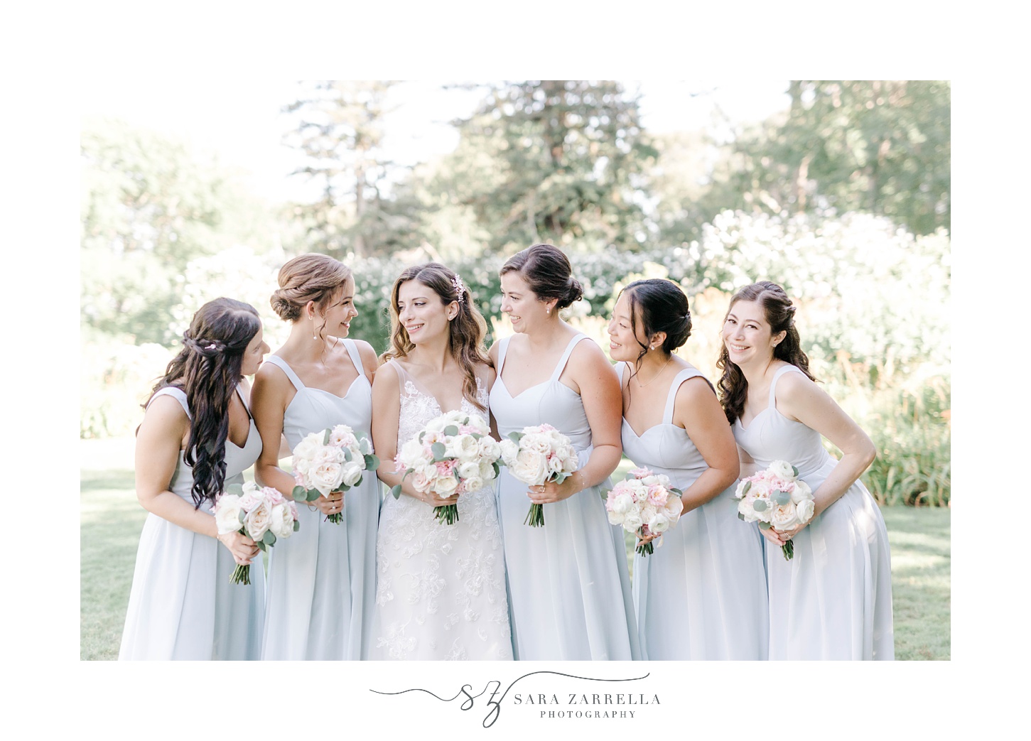 bride poses with bridesmaids in light blue gowns for RI wedding day