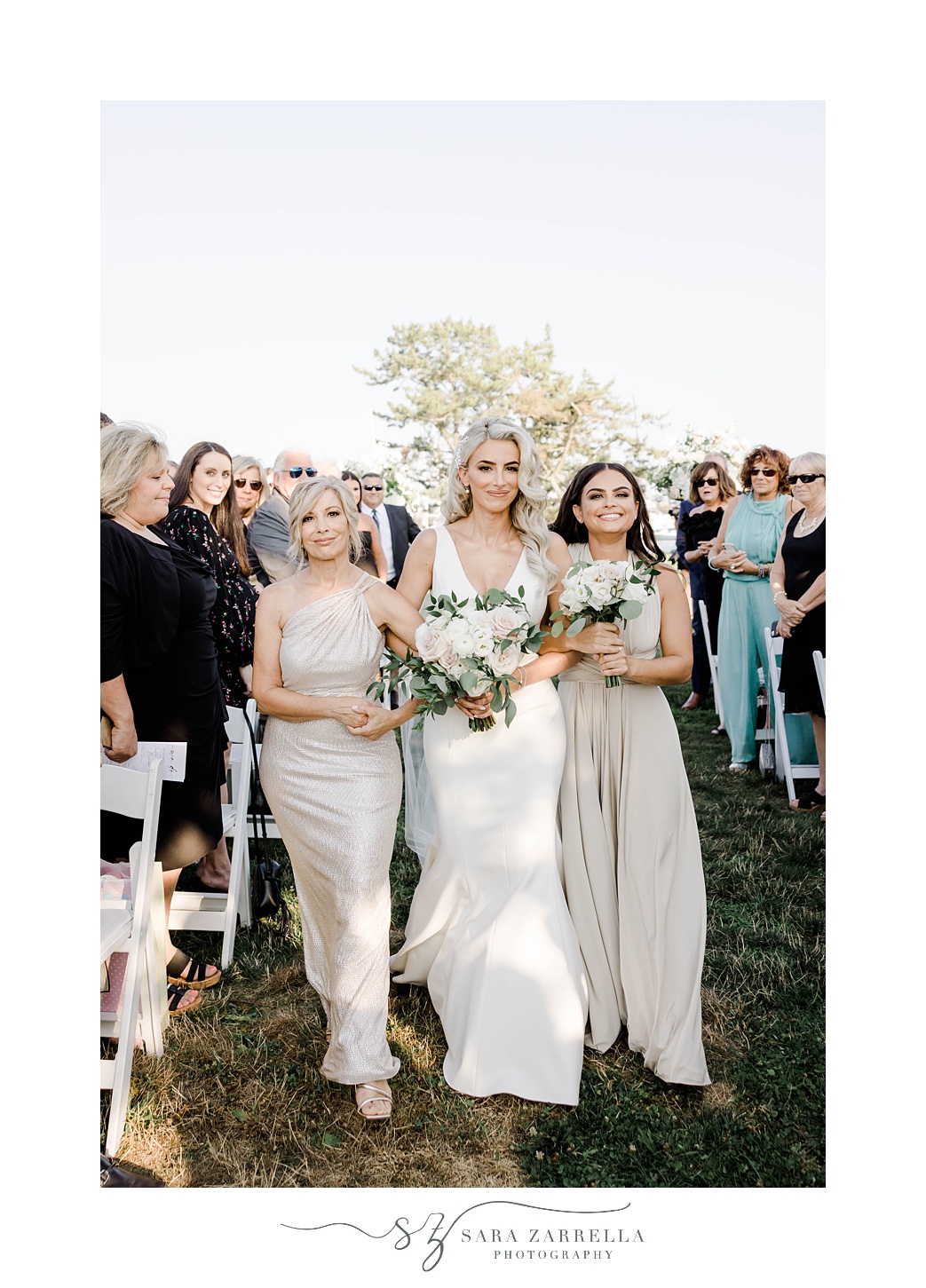 bride walks down aisle with mother and sister at Gurney’s Newport Resort
