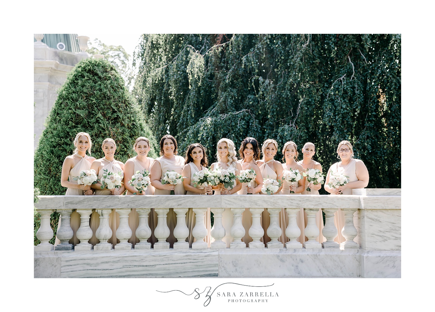 bride stands with bridesmaids by stone wall