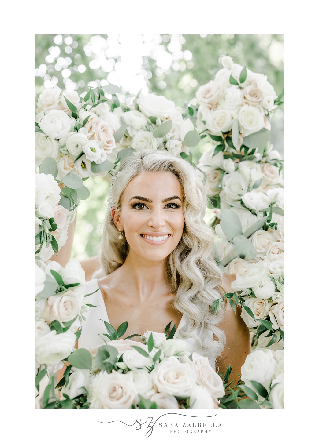 bride smiles in frame created by bridesmaids' bouquets