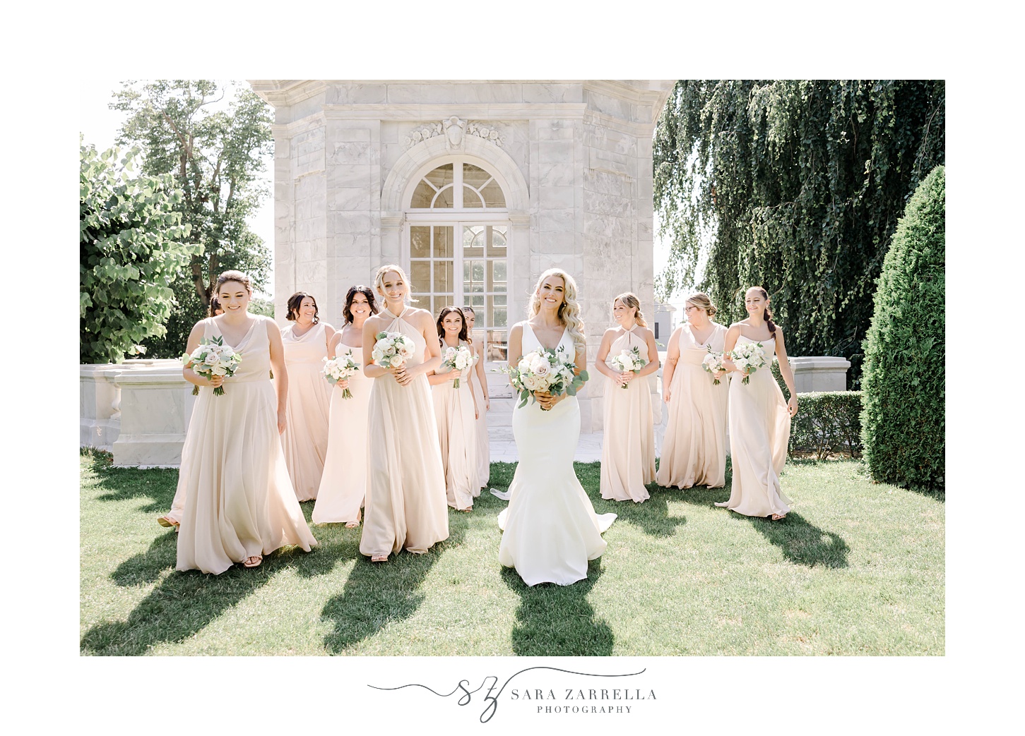 bride walks with bridesmaids in pink gowns across the lawn at The Elms