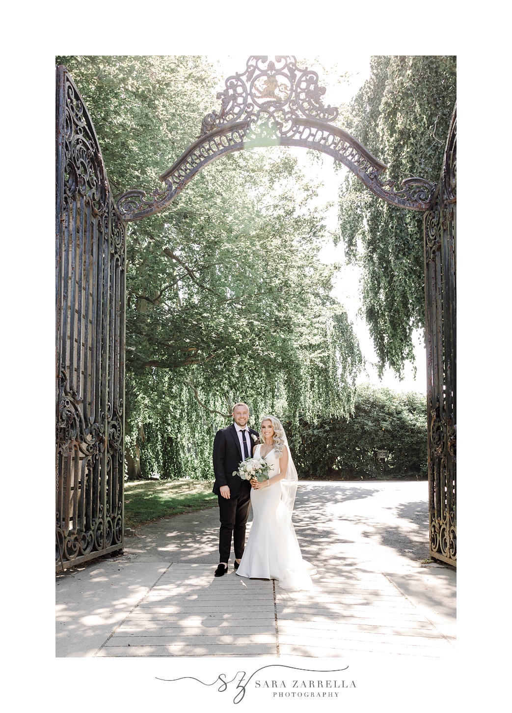 bride and groom pose under wrought iron gate at The Elms