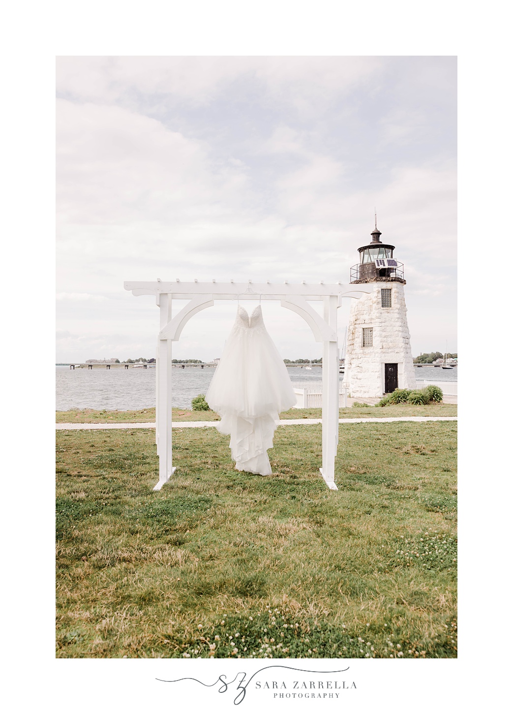 bride's wedding dress hangs on arch by Newport Lighthouse 