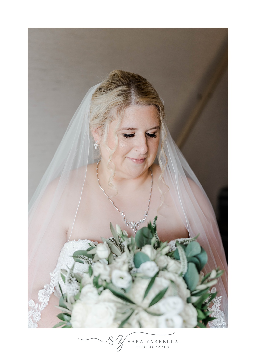 bride looks down at bouquet during bridal portraits at Gurney’s Newport