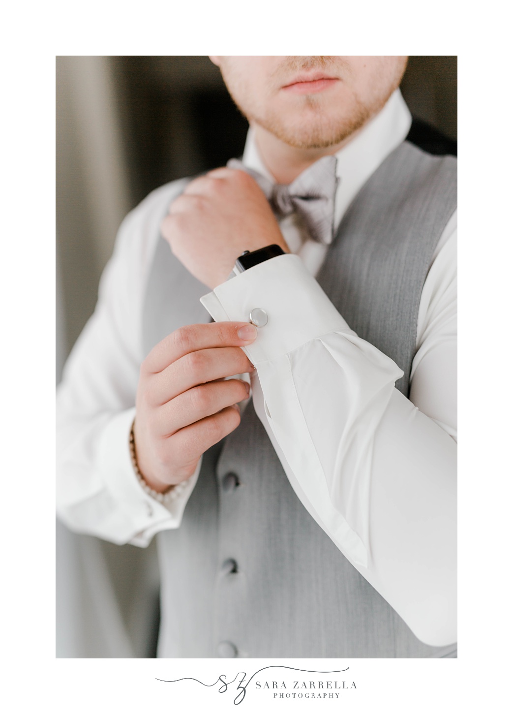 groom adjusts cufflinks on wedding morning 